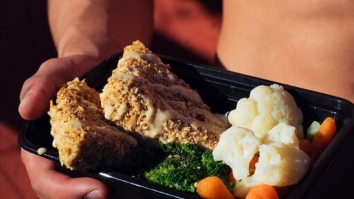 person holding cooked food on black factor 75 tray