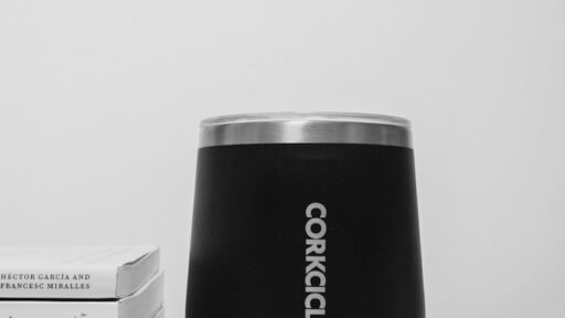 A black corkcicle cup sitting on top of a table next to a stack of books
