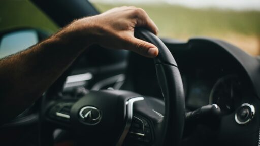 person holding black infiniti steering wheel