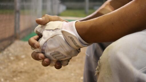 Close-up of a marucci baseball player's hands with marucci gloves during a game at dusk.