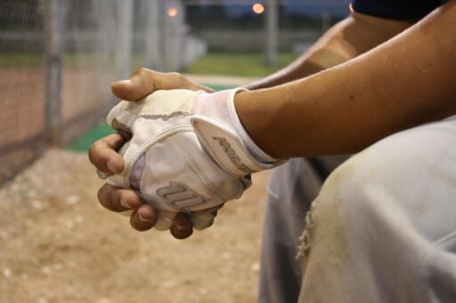 Close-up of a marucci baseball player's hands with marucci gloves during a game at dusk.