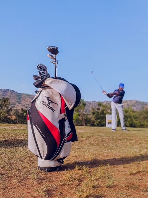 Mizuno Golf bag and player swinging under the clear blue sky on an Abuja course.