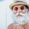 an AARP member with a white beard and mustache wearing a hat